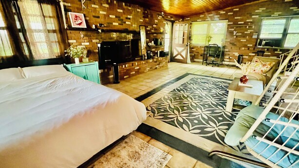 A bedroom with a large bed, a small sitting area with a chair and table, a fireplace, and a television. - Cozy, Private1-bedroom in charming Schenectady with Private Bathroom  (Schenectady)