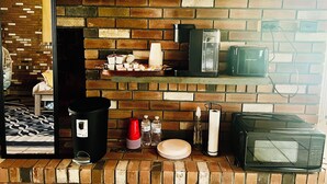 A kitchen with a brick wall, a coffee maker, a toaster, and a microwave. - Cozy, Private1-bedroom in charming Schenectady with Private Bathroom  (Schenectady)