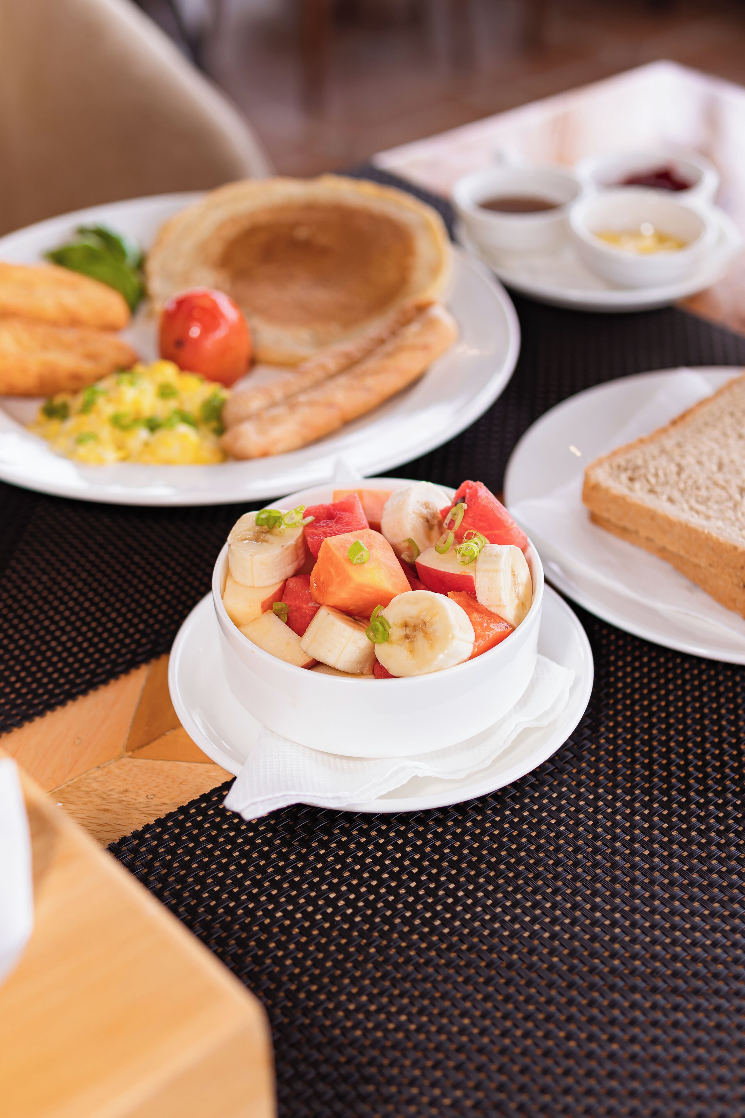A breakfast setting with various dishes including pancakes, toast, and a fruit bowl.