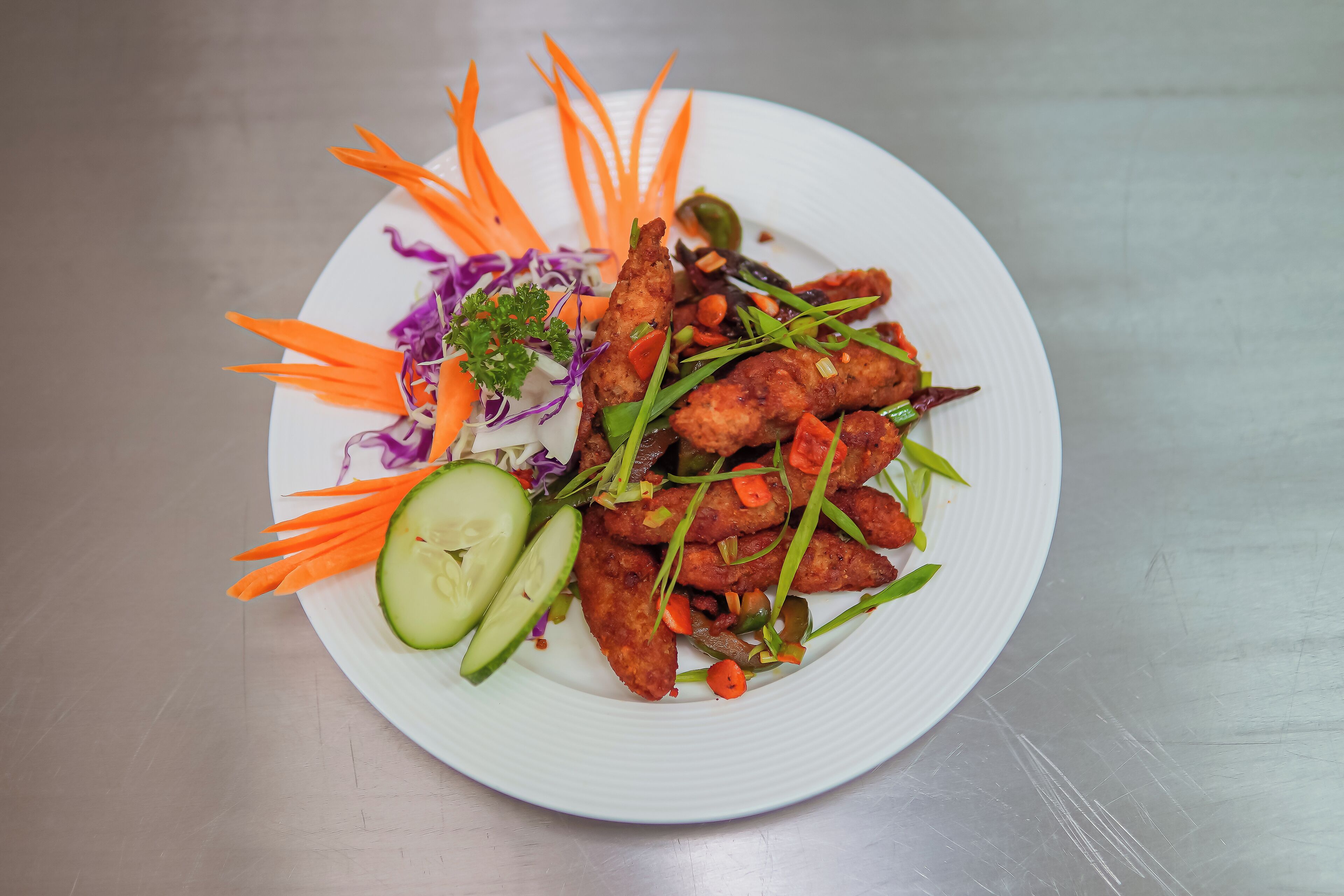 A plate of food with vegetables and a cucumber slice.