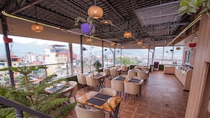 Un restaurante con terraza, ventanas amplias y plantas colgantes.