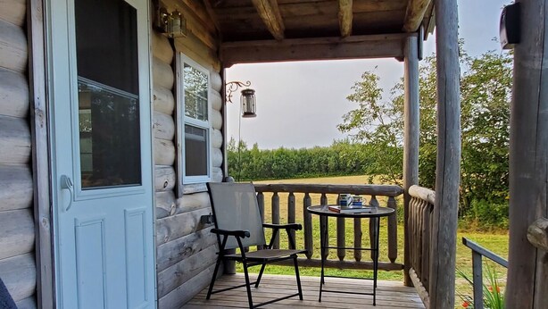 Une terrasse en bois avec un porche couvert, une table et deux chaises.