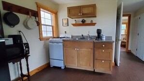 Une cuisine avec des meubles de rangement en bois, une cuisinière, une machine à café et un réfrigérateur.