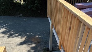 Una escalera de madera que lleva a un área de terraza con un camino de grava y árboles al fondo.