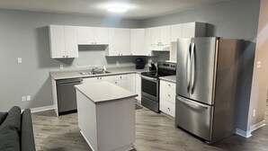 Una cocina moderna con armarios blancos, electrodomésticos de acero inoxidable y una isla central.