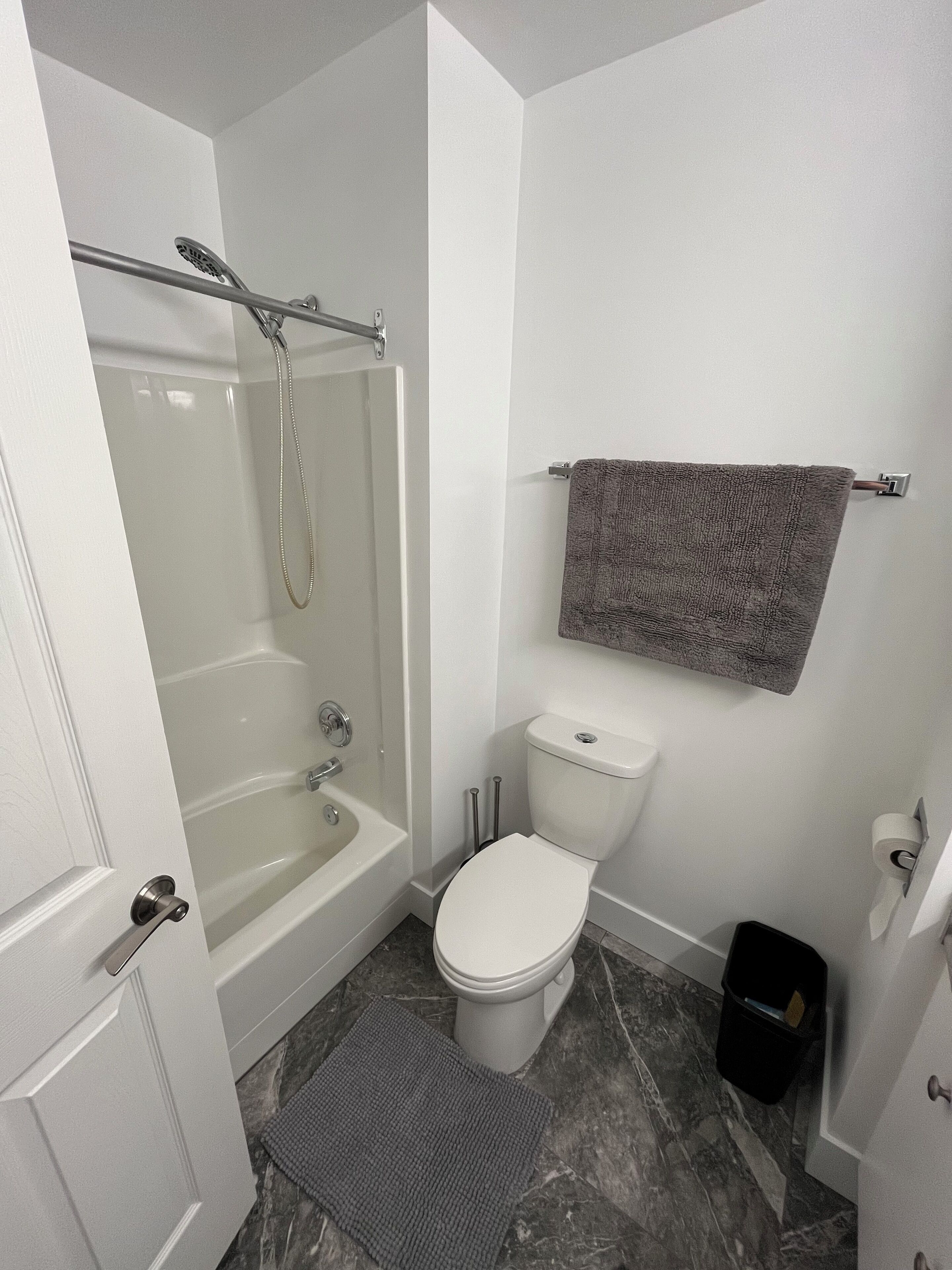 A bathroom with a bathtub, toilet, and a towel rack.