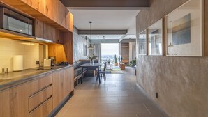 Una cocina moderna con armarios de madera, un comedor con mesa y sillas, y vistas de la ciudad a través de amplios ventanales.