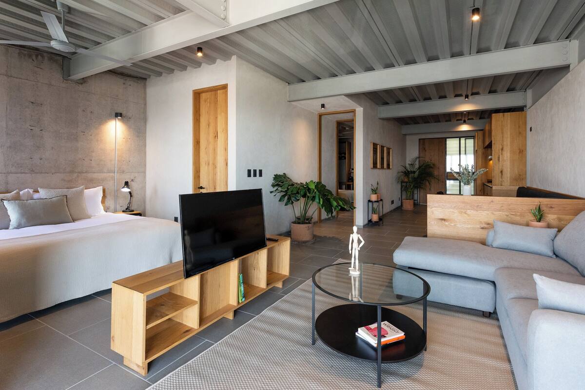 Una sala moderna con cama, sofá, televisor y mesa de centro.