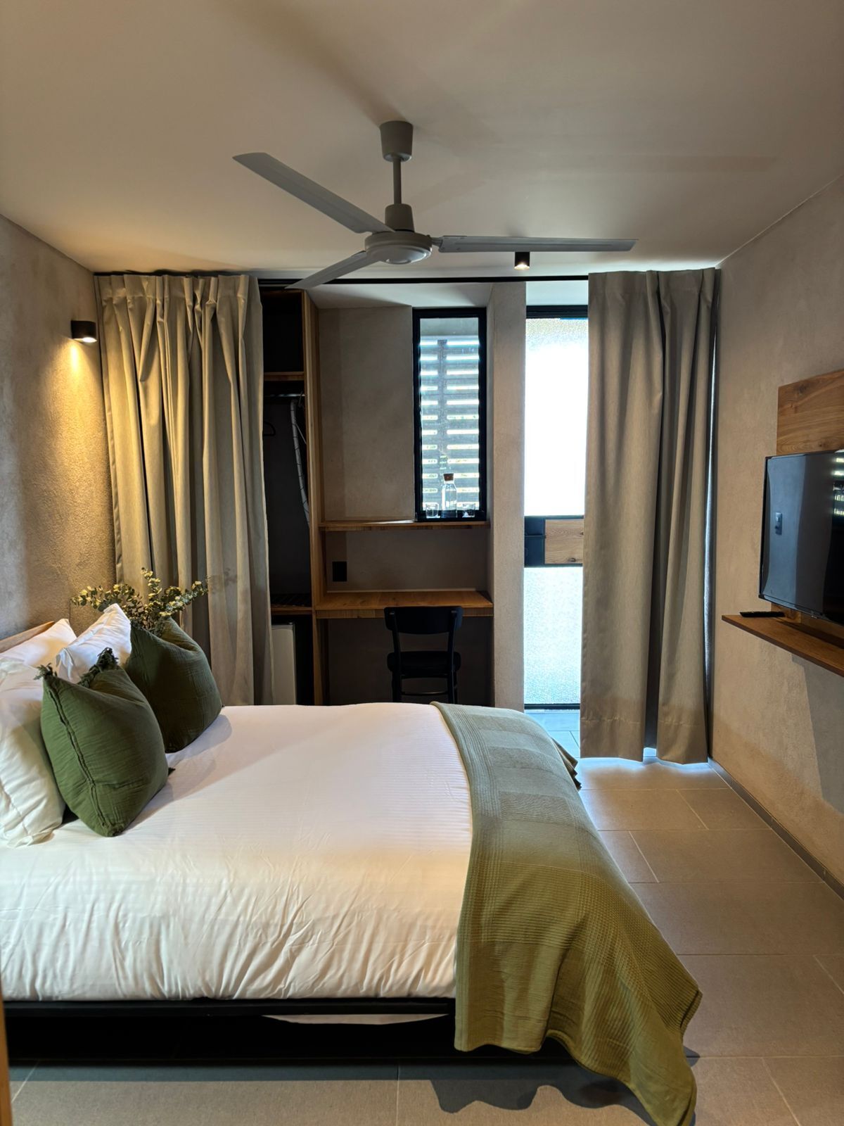 Une chambre d’hôtel moderne équipée d’un lit, d’un bureau et d’une télévision.