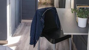 A compact kitchen with a dark gray exterior, a small dining area with a white table and a black chair, and a potted plant on the table. - Luma Boutique Hotel (San Carlos de Bariloche)