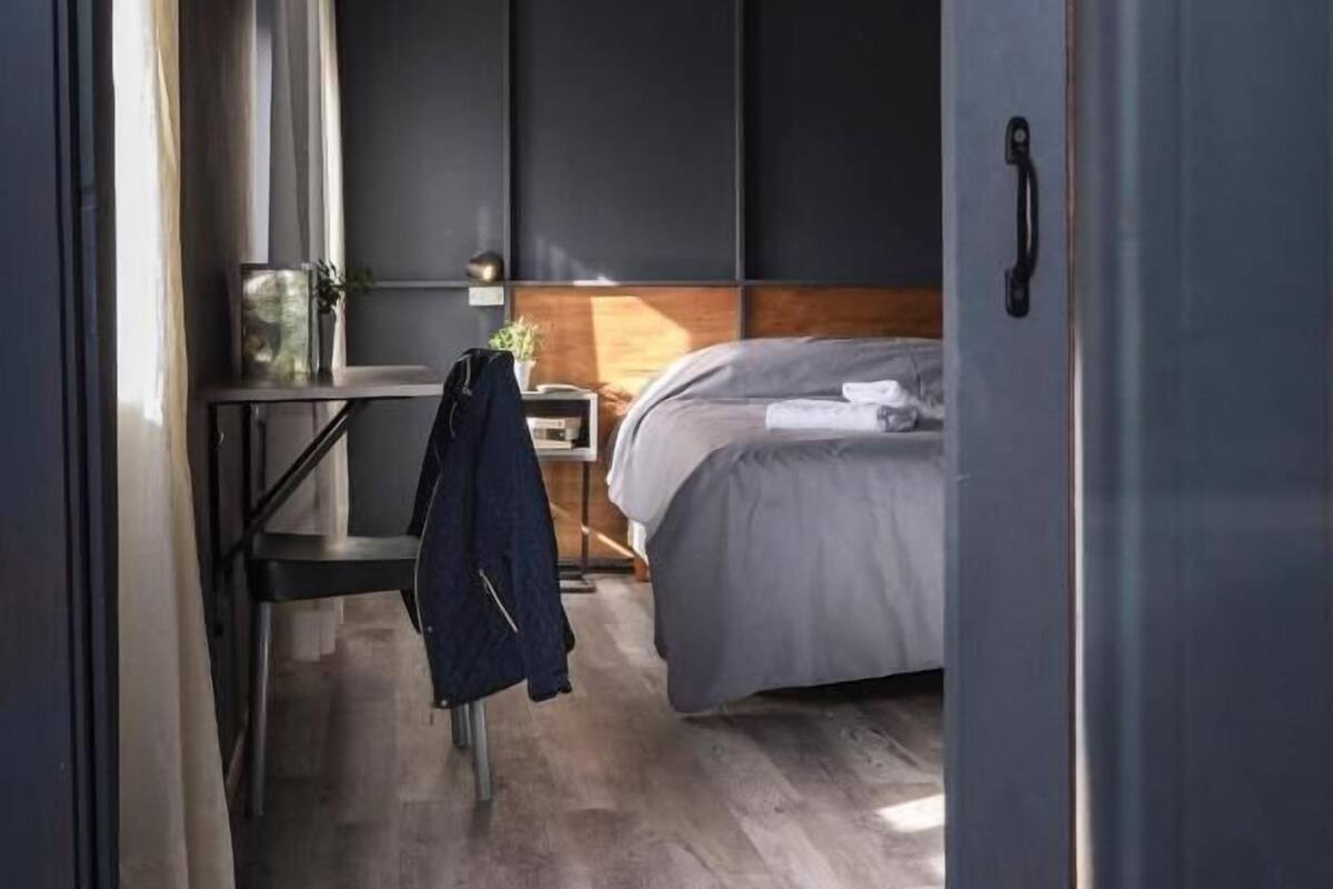 A bedroom with a bed, a desk, and a chair.