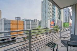 A balcony with a view of high-rise buildings, a metal railing, and a small table. - Downtown Phoenix Retreat | Walk to Arts District (Phoenix)