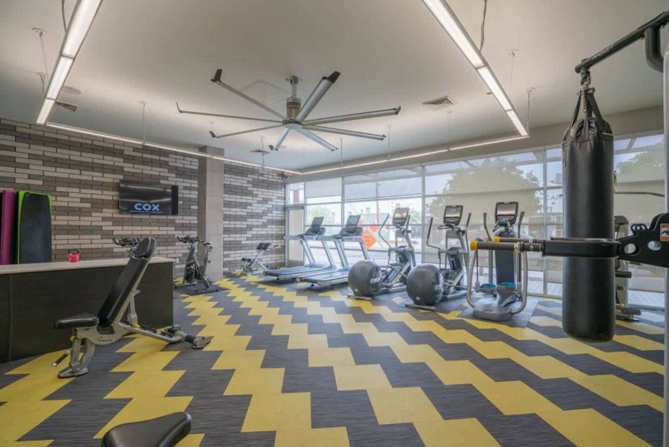 A gym with exercise equipment, a punching bag, and a COX sign on the wall.