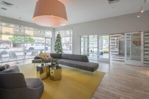 A modern lobby with a large sofa, a coffee table, and a Christmas tree. - Downtown Phoenix Retreat | Walk to Arts District (Phoenix)