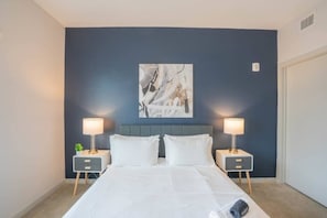 A bedroom with a bed, two bedside tables, and a wall-mounted abstract painting. - Downtown Phoenix Retreat | Walk to Arts District (Phoenix)
