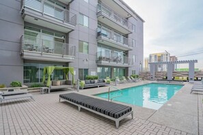 A modern building with a swimming pool, outdoor seating, and a view of other buildings. - Downtown Phoenix Retreat | Walk to Arts District (Phoenix)