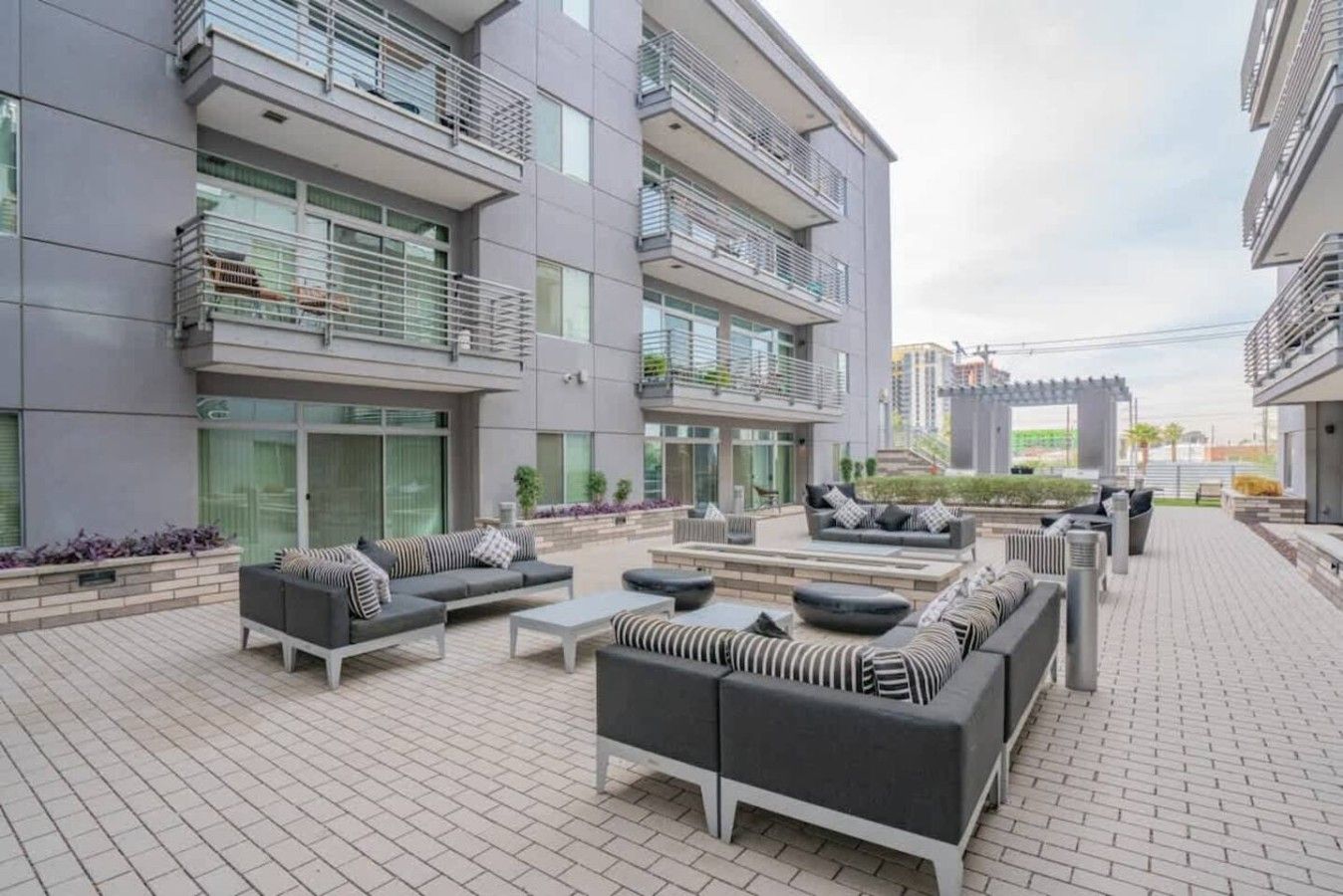 A modern outdoor living area with multiple seating arrangements, including sofas and chairs, and a flat roof terrace.
