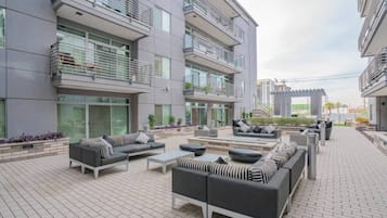 A modern outdoor living area with multiple seating arrangements, including sofas and chairs, and a flat roof terrace.