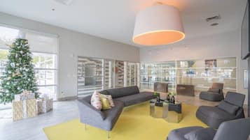 Un salón moderno con un sofá gris, un tapete amarillo y un ventanal grande.