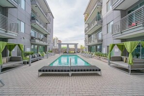 A modern outdoor pool area with a rectangular pool, lounge chairs, and a pergola structure. - Downtown Phoenix Retreat | Walk to Arts District (Phoenix)