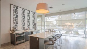 A modern kitchen with a central island, bar stools, and a large window offering a view of parked cars. - Downtown Phoenix Retreat | Walk to Arts District (Phoenix)