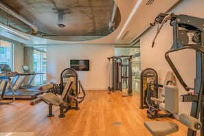 Ett gym med löpband, styrketräningsmaskiner och en tv på väggen.