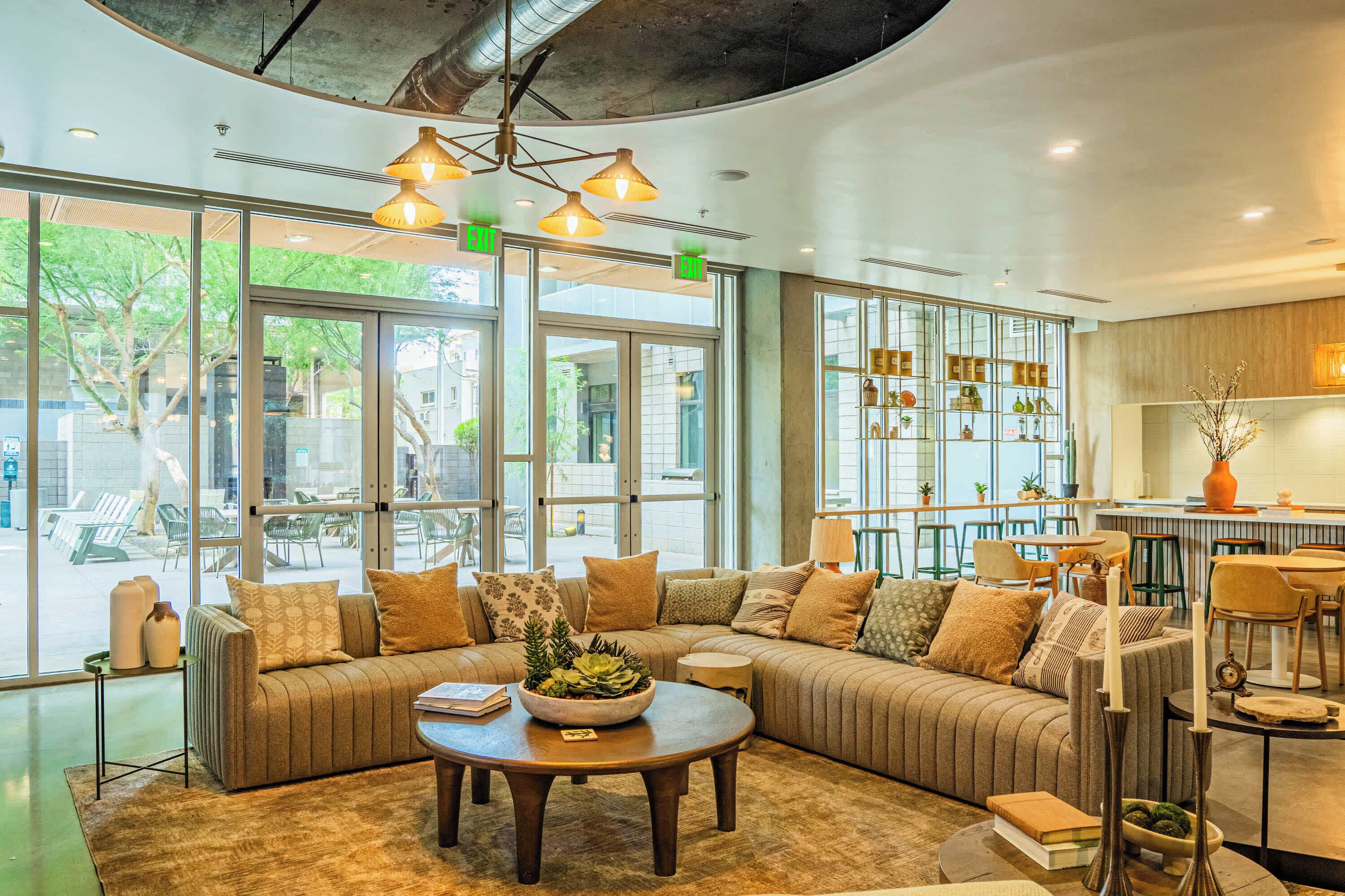 A modern interior with a sectional sofa, a round coffee table, and a dining area with chairs and a bar.
