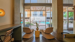 Zona de recepción con sillas de mimbre, una planta en maceta y vistas a una piscina y área de estar al aire libre.