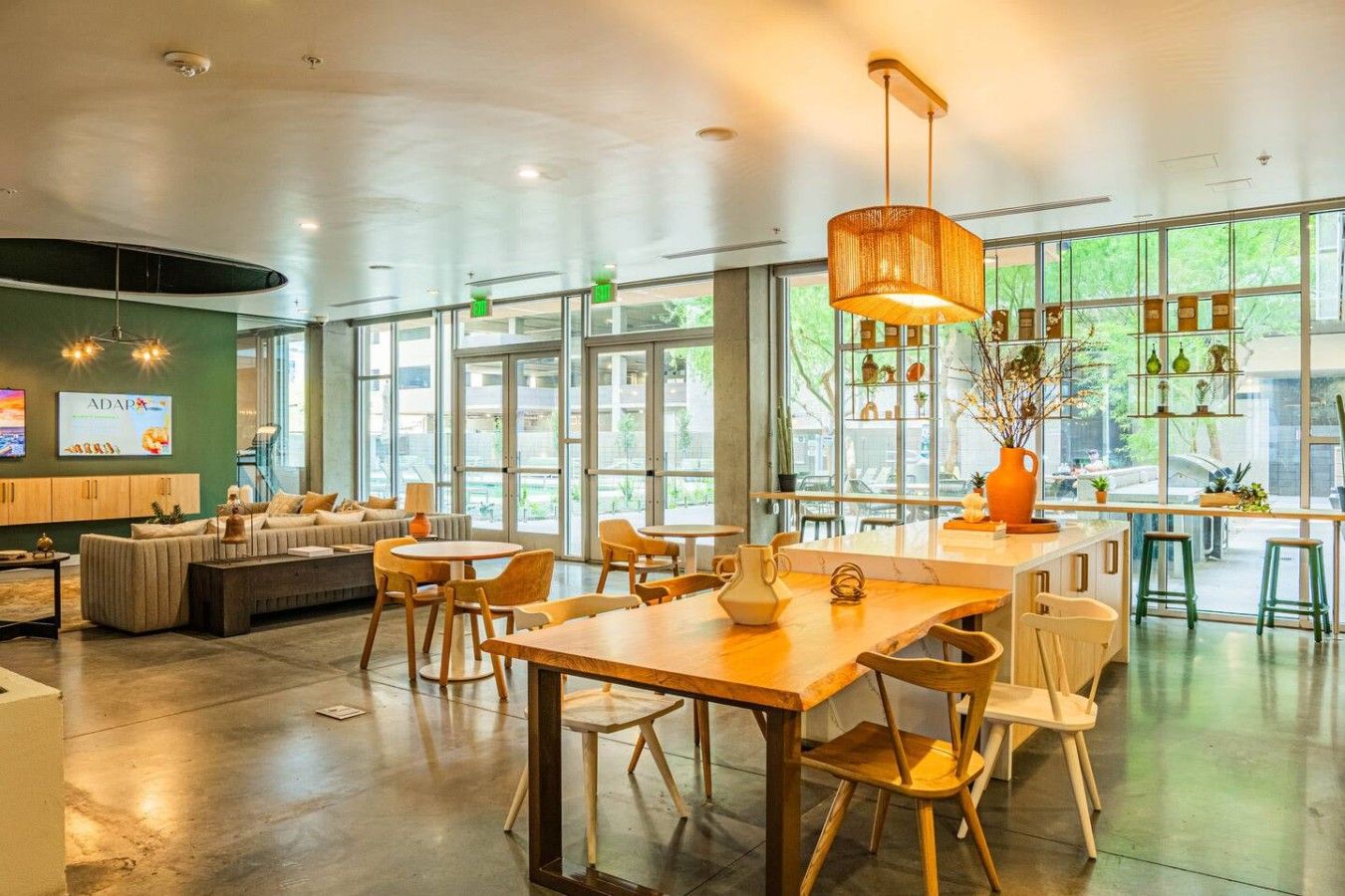 A spacious indoor area with a mix of seating arrangements, including tables and chairs, and a large window providing natural light.