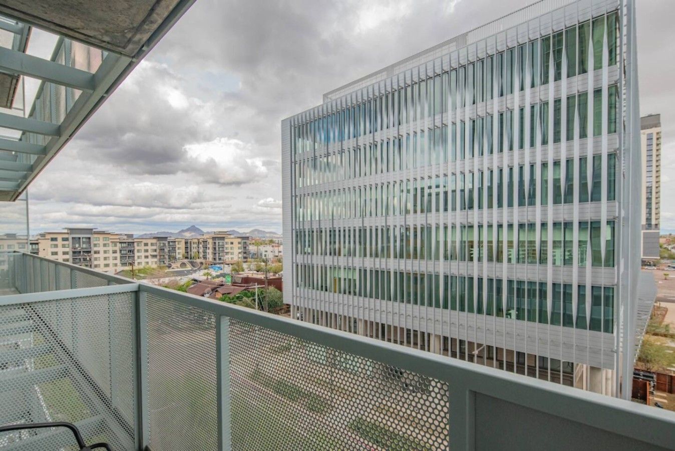 A modern building with a grid of windows and a balcony with a metal railing.