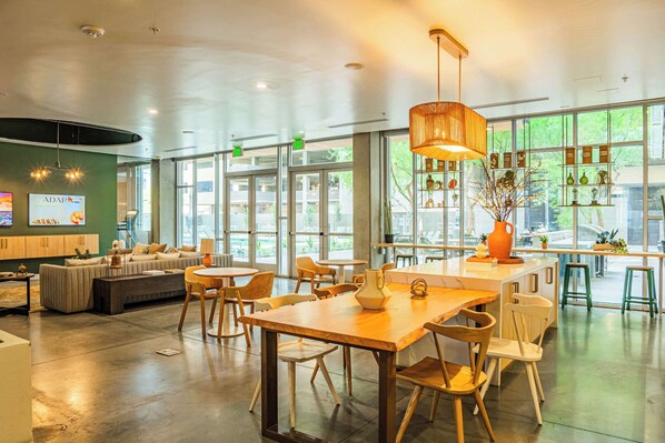 A spacious, well-lit interior with a modern dining area, comfortable seating, and large windows offering natural light and views. - Central Downtown PHX | Pool, Gym, Parking, Balcony (Phoenix)
