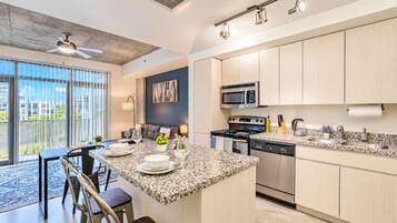 A modern kitchen with a central island, stainless steel appliances, and a dining area with a view.