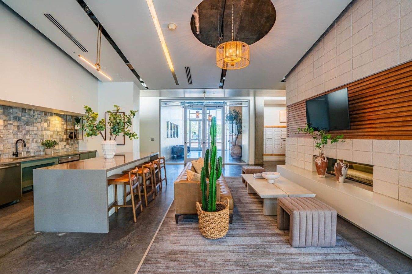 A modern kitchen with a central island, bar stools, and a dining area with a cactus centerpiece.