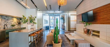 Una cocina moderna con una isla central, taburetes de bar y un comedor con un cactus como centro de mesa.