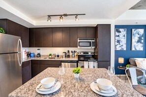 A modern kitchen with dark cabinets, stainless steel appliances, and a granite countertop.