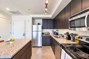 Een moderne keuken met donkere kastjes, roestvrijstalen apparatuur, granieten aanrechtbladen en een centraal eiland.