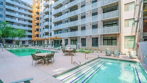 Un immeuble d’appartements moderne doté d’une piscine, d’un espace extérieur aménagé et d’un jardin bien entretenu.