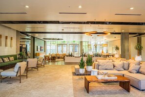 A spacious lobby with a modern design, featuring a central seating area with sofas and armchairs, a coffee table, and potted plants. - PHX DT Apartment with Balcony + Gym + Pool Parking (Phoenix)