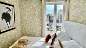 A hotel room with a bed, pillows, a framed picture, and a window with curtains. - Le Petit Appartement du 10honfleur, Calme, Quartier Ste Catherine (Honfleur)