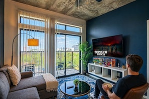 A living room with a sofa, a coffee table, a TV, and a balcony with a view. - Modern PHX Apt w/ Pool, Gym, Balcony + W/D (Phoenix)