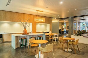 Een moderne keuken met een centraal eiland, barstoelen en ronde tafels met stoelen.