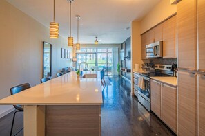 A modern kitchen with a central island, stainless steel appliances, and pendant lighting.