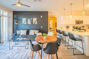 A modern kitchen with a central island, bar stools, and a dining area with a round table and chairs. - DT Phoenix | Pool, Gym, Parking, W/D Near Airport (Phoenix)