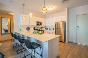 A modern kitchen with a central island, stainless steel appliances, and pendant lighting. - DT Phoenix | Pool, Gym, Parking, W/D Near Airport (Phoenix)