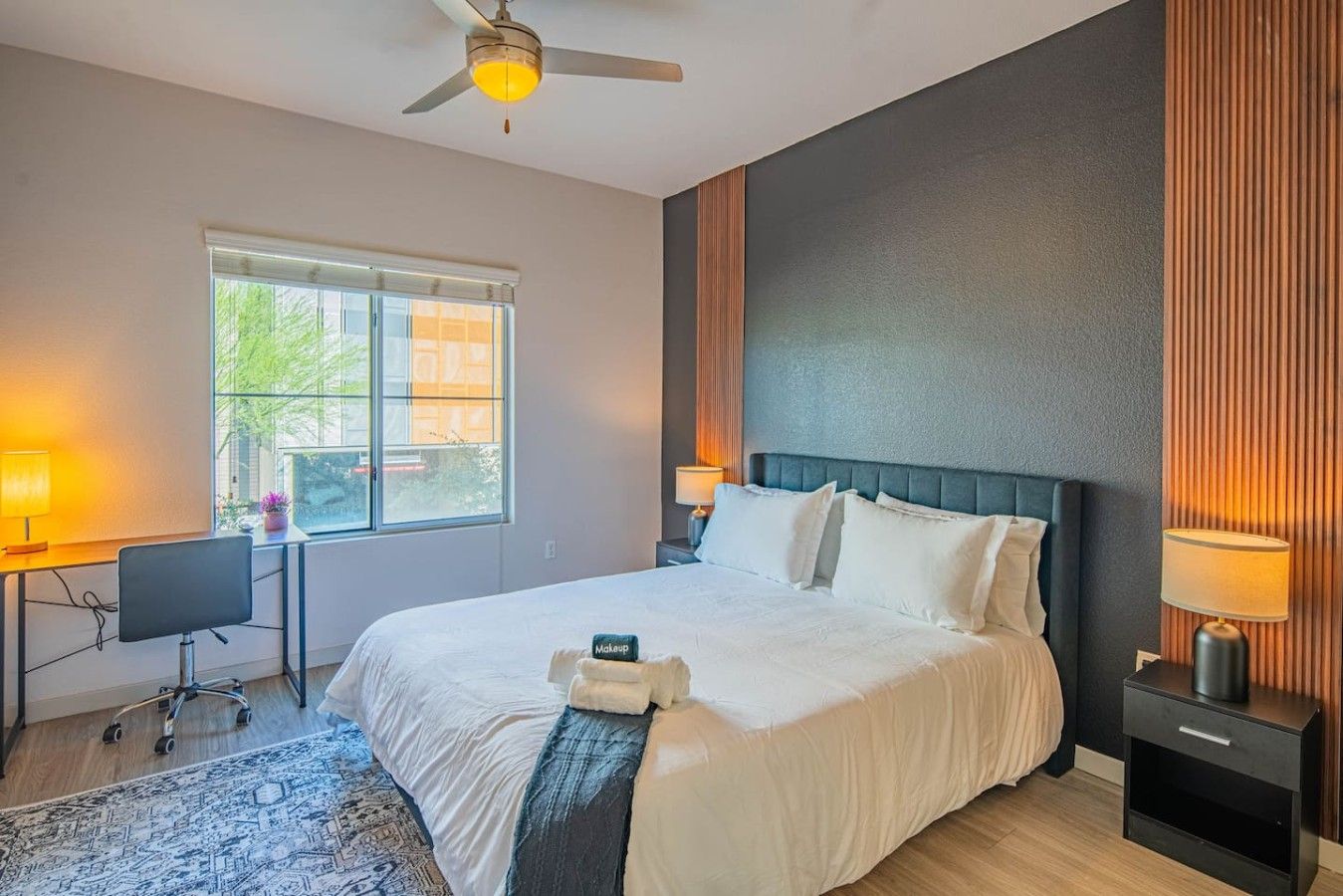 A hotel room with a bed, desk, chair, and a window with a view.