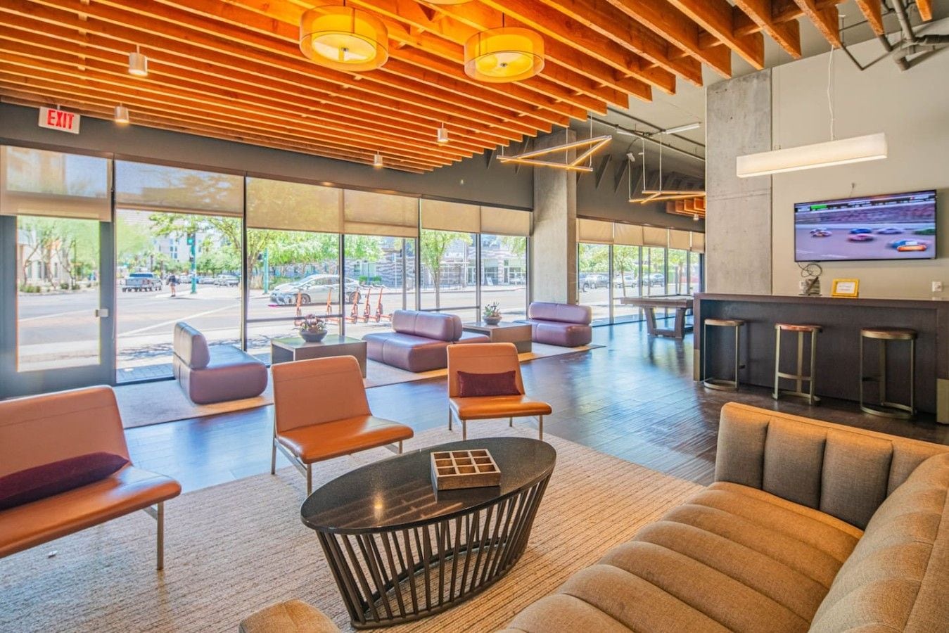 A modern lobby with seating areas, a reception desk, and a television screen.