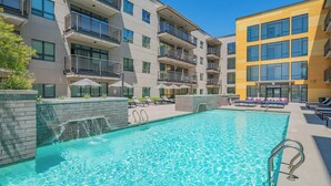 A modern hotel with a swimming pool, multiple balconies, and outdoor seating areas.