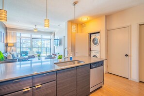 A modern kitchen with a central island, built-in dishwasher, and a washing machine in the background.