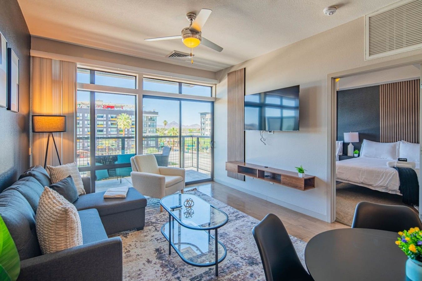 Een moderne hotelkamer met een bank, fauteuil en een aan de muur bevestigde televisie.