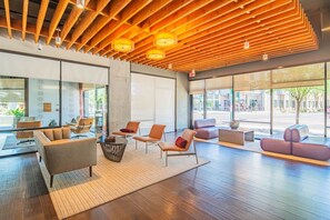 A modern lobby with wooden ceiling beams, large windows, and contemporary seating arrangements.